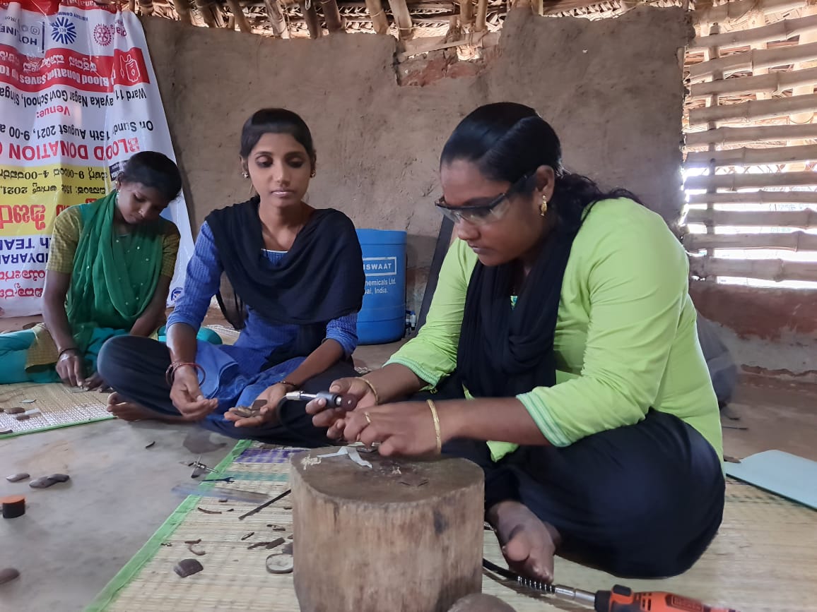 Worker wearing safety glasses uses power tools to craft product while another watches