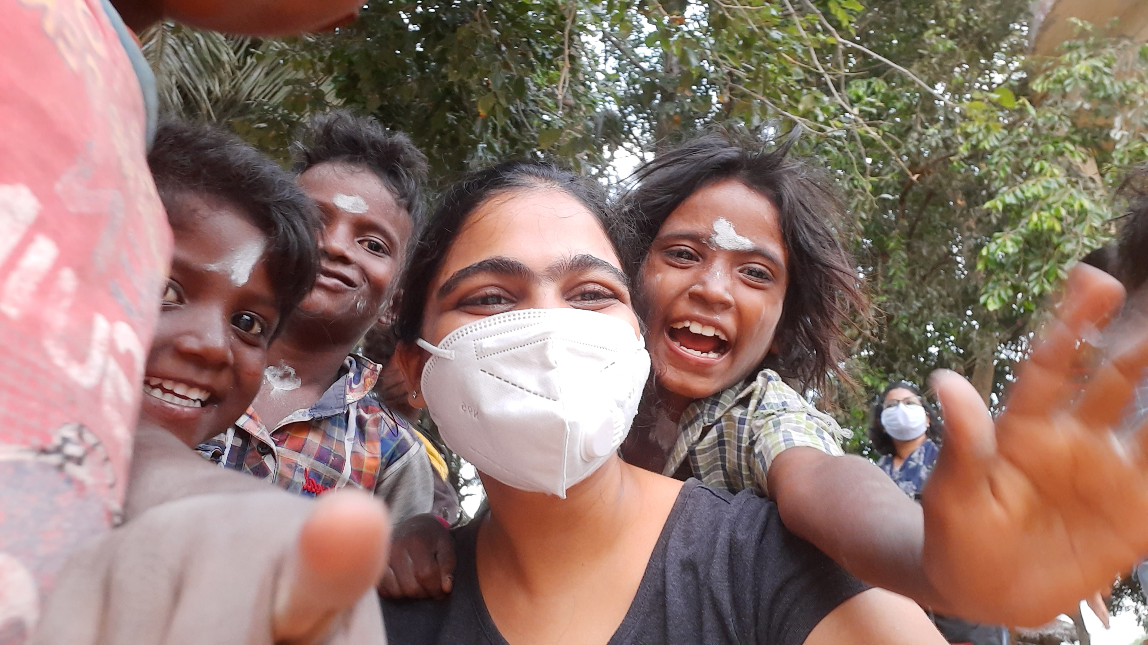 Selfie by masked student with several of the workforce's children smiling at the camera