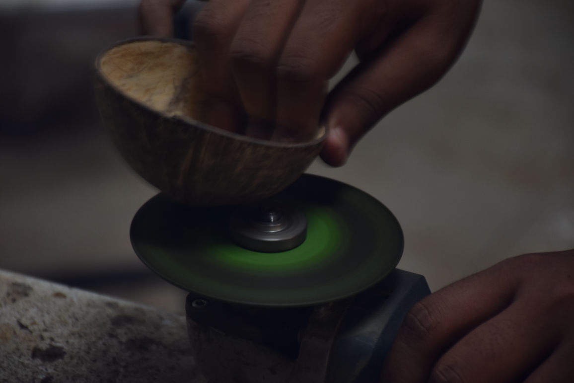 Dried coconut shell being ground down by a disc grinder